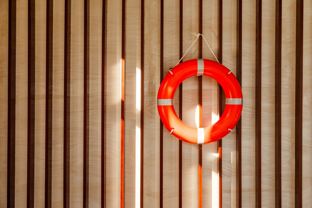 Red lifebuoy hanging on blue wooden wall of a port building